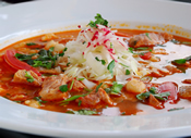 Pasole topped with radish & cilantro in a large white bowl