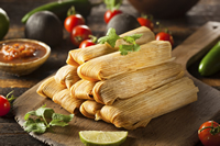 9 tamales stacked on a wood cutting board