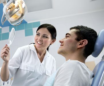 Dentist showing patient their teeth in a hand held mirror