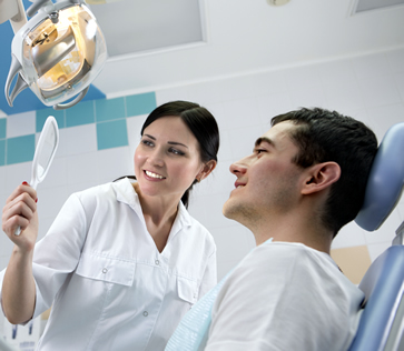 Dentist showing patient their teeth in a hand held mirror