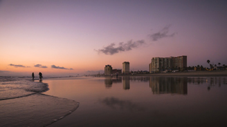 Walking on the beach in Mexico with resorts in background