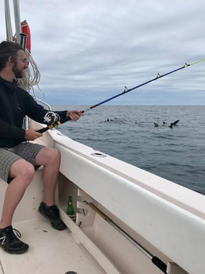 Man fishing off a boat with dolphins in the background, in Mexico