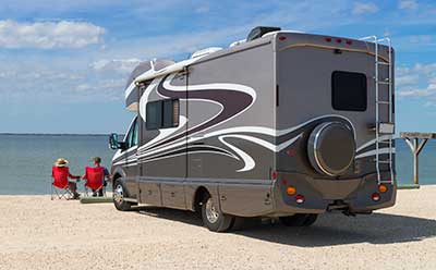 RV Couple sitting outside RV parked on Beach