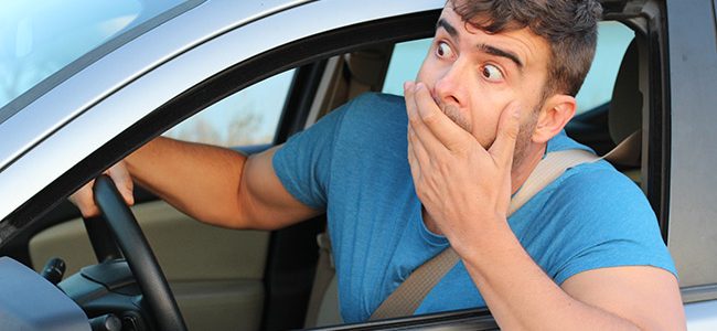 Man looking out driver's side window with hand over mouth after having an accident