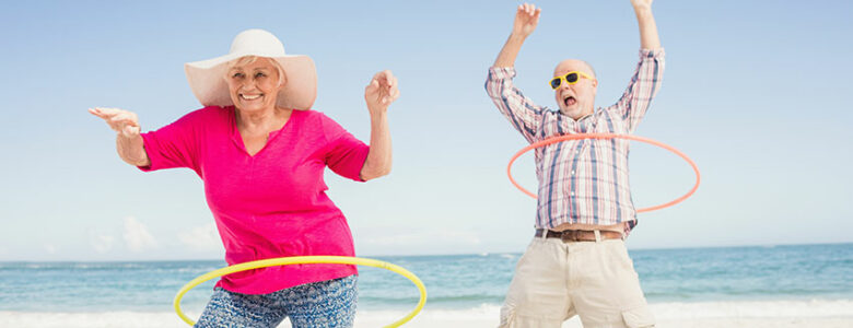 Retired couple hoolahooping on a Mexican beach