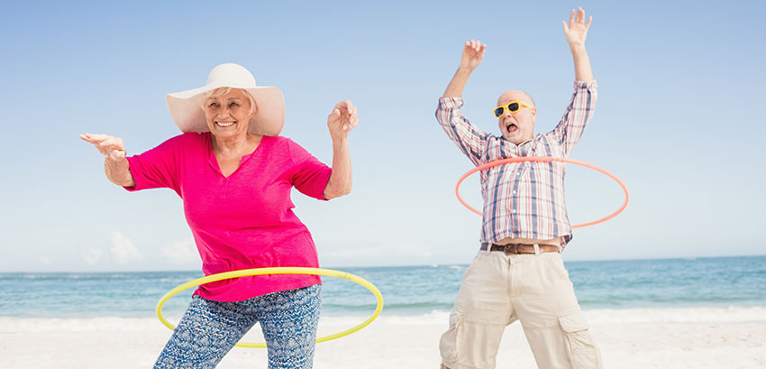 Retired couple hoolahooping on a Mexican beach